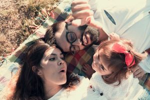 Familia relajada en el suelo del monte sobre una manta, el padre mirando a la hija. Fotografo de familias en Vigo, Galicia.