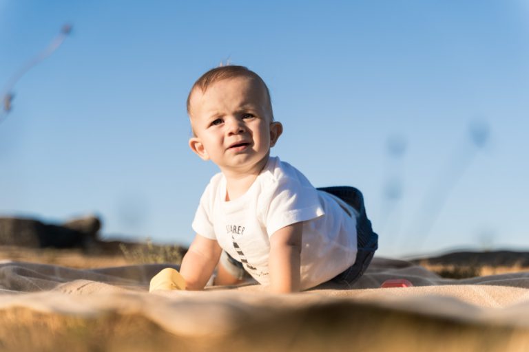 Bebé gateando sobre el césped, mirando con curiosidad, con luz natural. Fotografo de bebes en Galicia, explorando el mundo.
